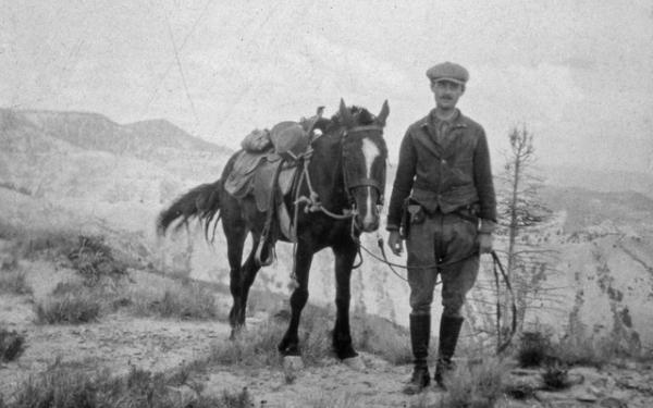black and white photo of edmund spieker doing field work while leading a horse