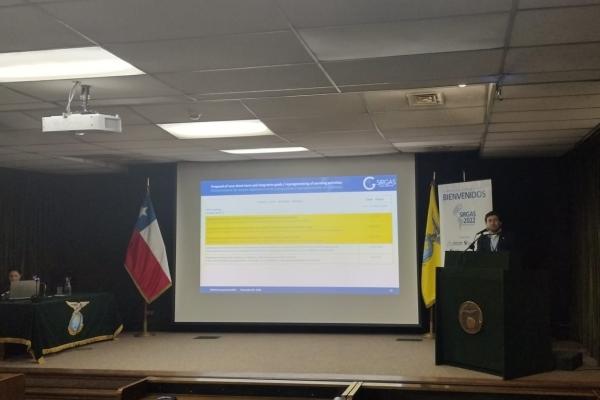Dr. Demián Gómez presenting during the 2022 SIRGAS symposium. A projected screen shows an image of findings