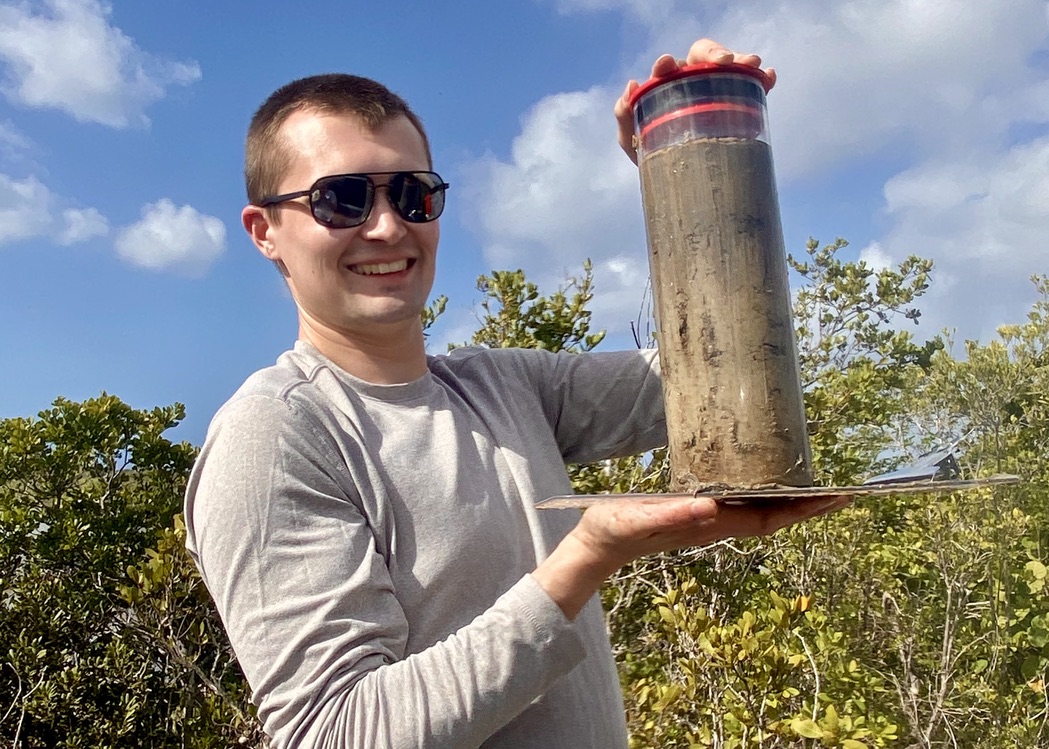 Prescott smiles while holding a sediment core