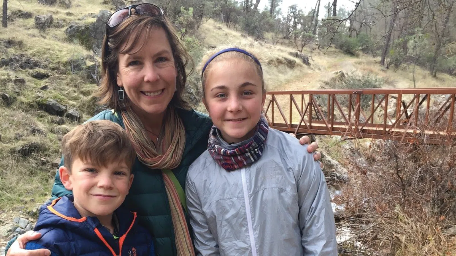 Monique Gaido smiles on a hiking trip while hugging her son and daughter