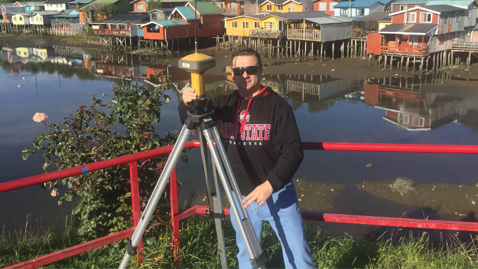 Julio carrying out field work in front of a lake with colorful houses populating the shoreline