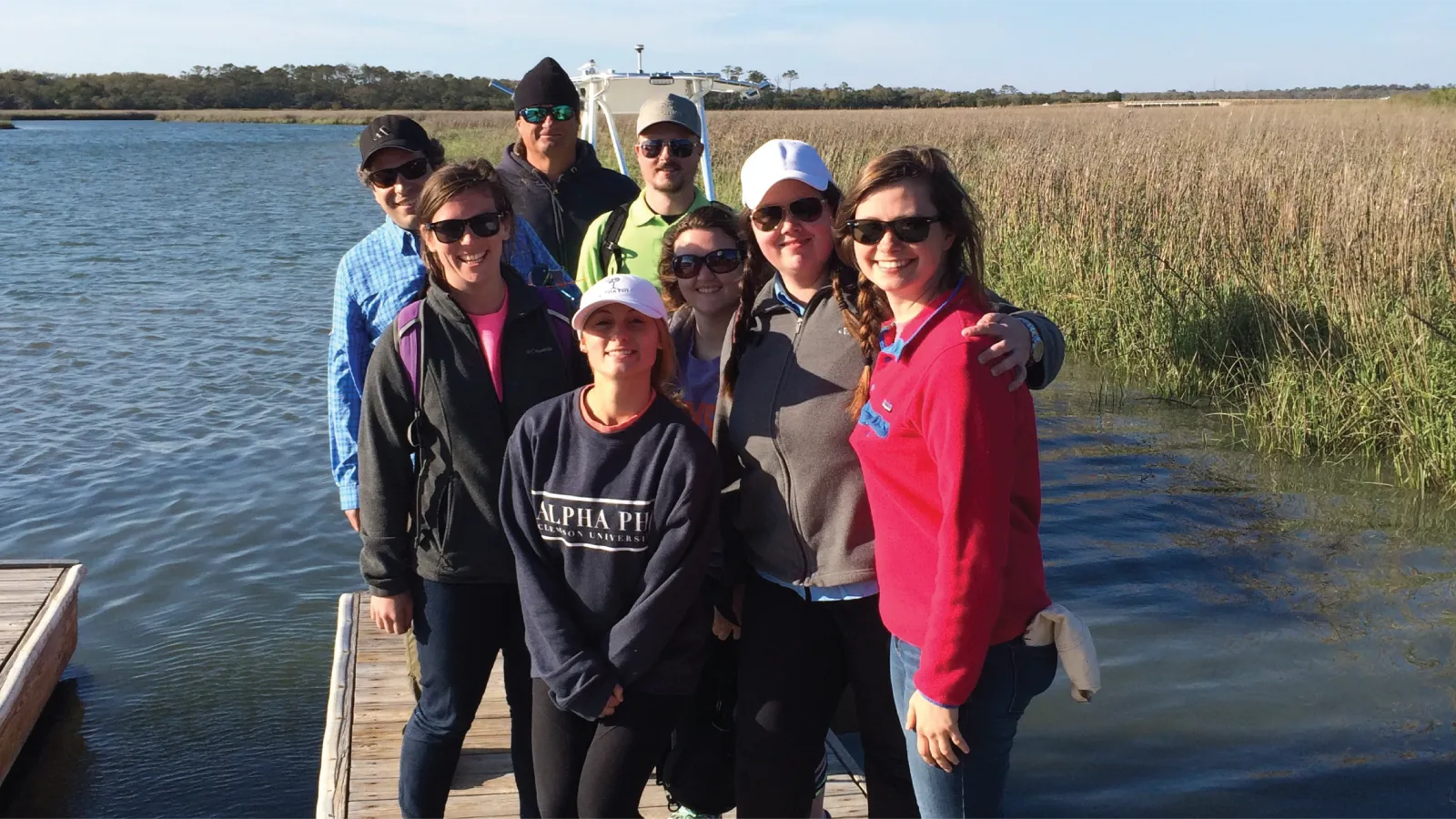 Kelly smiles on a shoreline with happy students