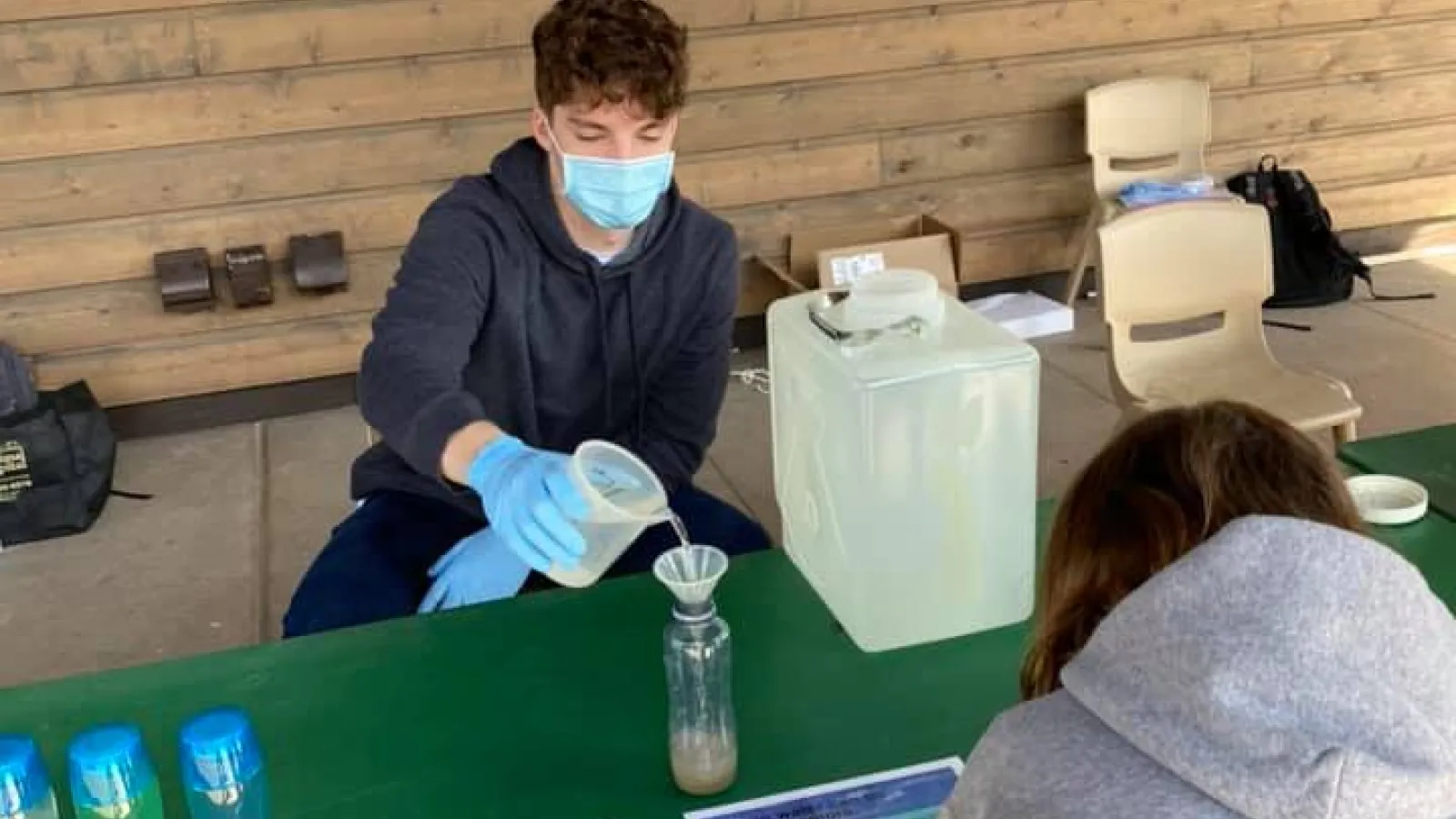 Man helps pour sand into jar 