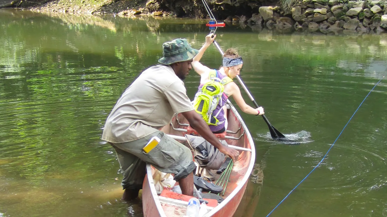 Alumni Deon Knights and Kelsey Snodgrass undertake hydrology fieldwork in a canoe on a river for their graduate research projects.