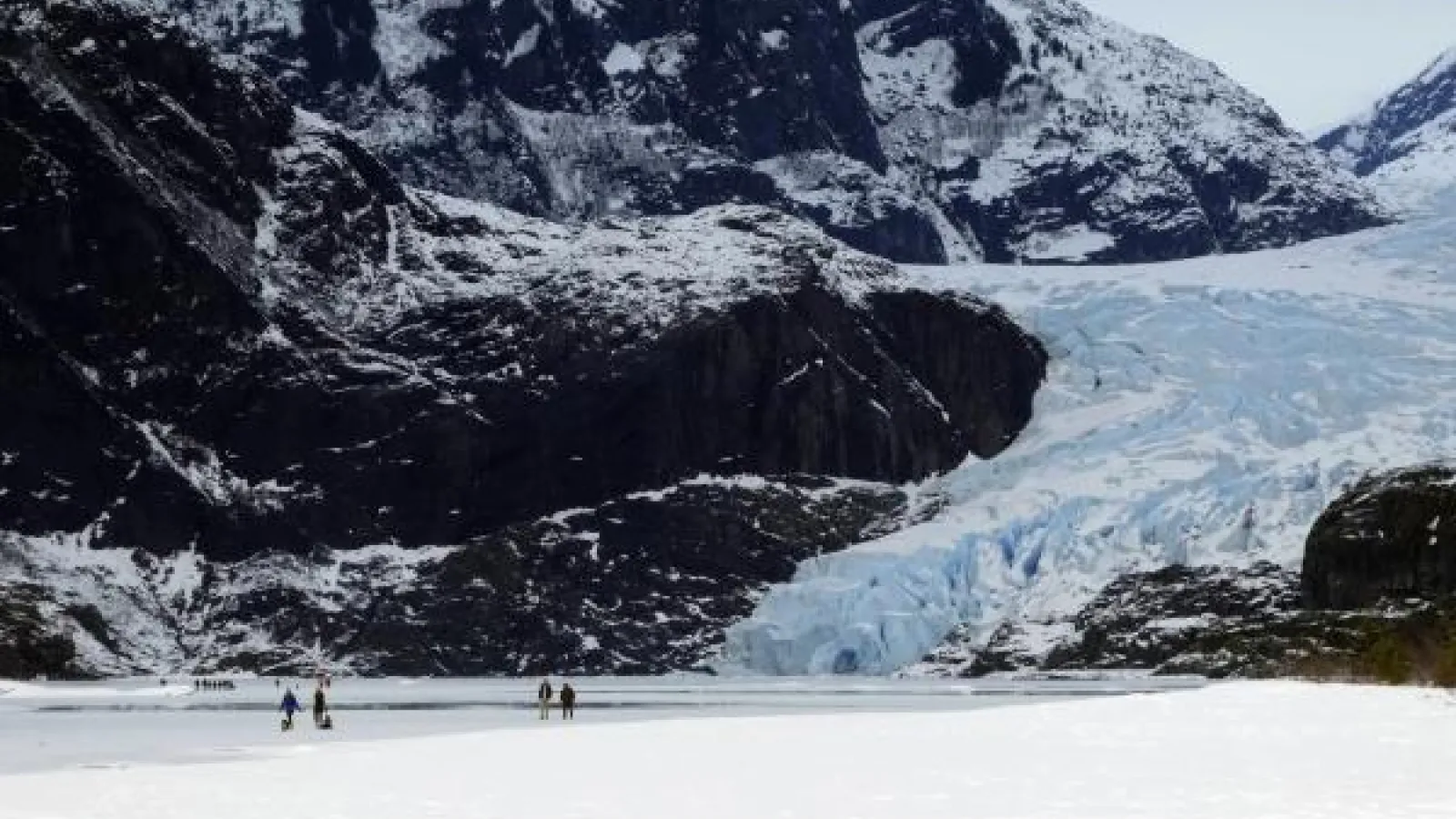 FILE - People walk on a frozen Mendenhall Lake, with Mendenhall Glacier in the background, Feb. 18, 2024, in Juneau, Alaska. A new study says the melting of Alaska’s Juneau icefield, home to more than 1,000 glaciers, is accelerating. Becky Bohrer/AP.