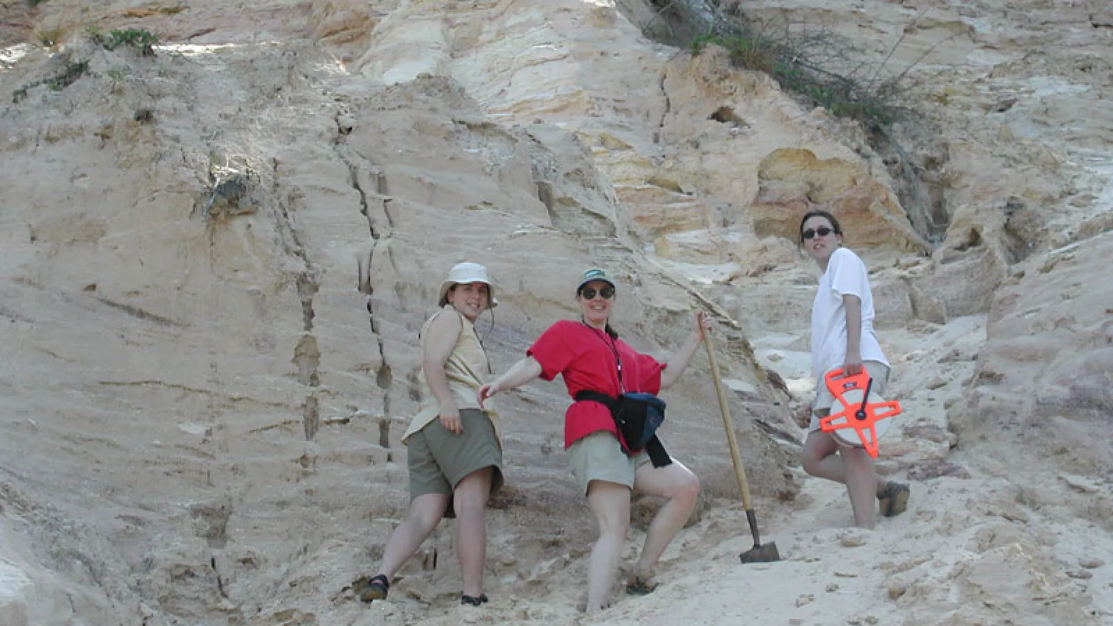 Three members of the Earth Sciences grad program pose for picture near rocky cliffside.