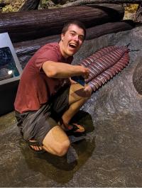 Andrew Sever smiling next to a model trilobite