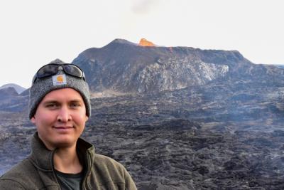 Ken Peterman stands in front of a volcano 
