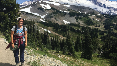 Abbie Bowman hiking near a snowy mountain with pine trees