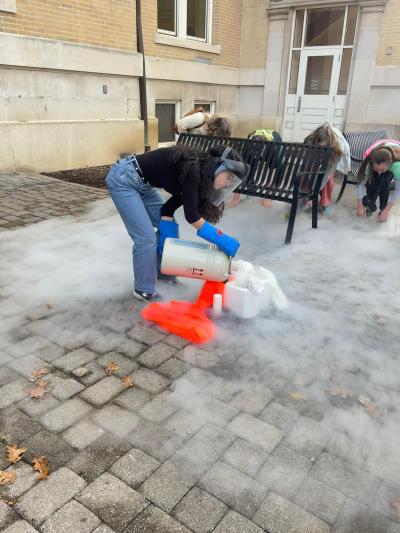 Batoul Saad doing a dry ice activity where she poured dry ice on fruit and then broke it on the floor.