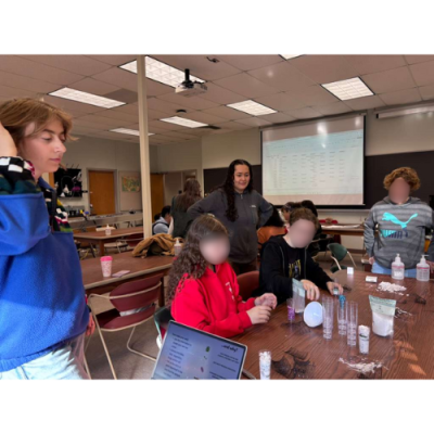 This image shows Denise Mondragon and Emerald Goldbaum leading a polar research activity. They had students make ice cores and explain the different things that you can find trapped in them.