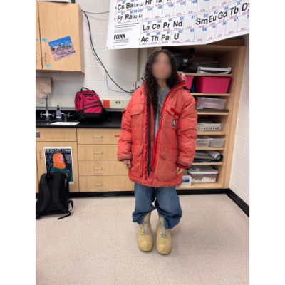 This is an image of one of the high school students at Westerville Central High School wearing a big red jacket and bunny boots, attire worn by scientists in Antarctica. Presenter, Denise Mondragon, brought clothes, rocks, and videos from Antarctica to share with students.