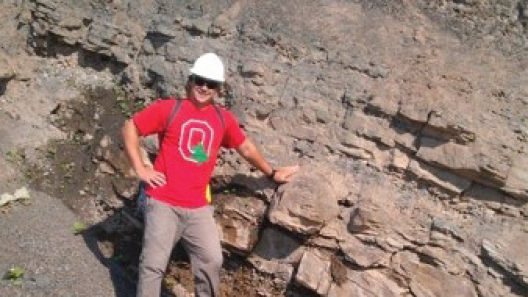 Bill Magee wearing a "Block O" shirt leaning against an outcrop