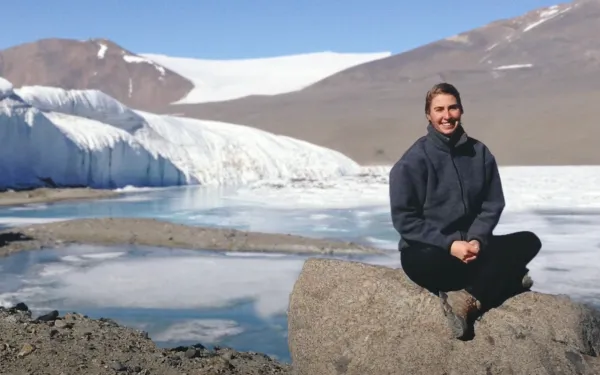 Sydney Olund sitting on a rock in front of a glacier