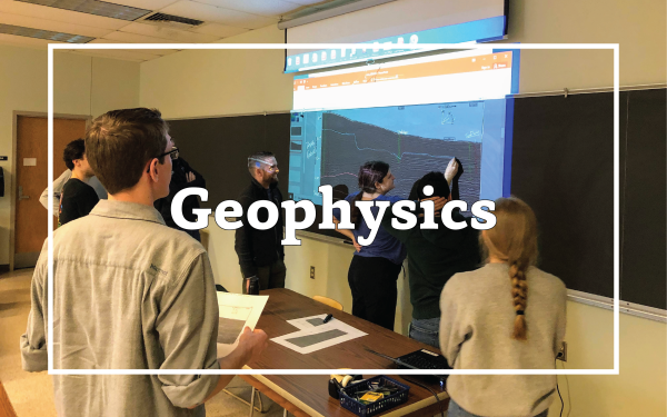 Photo of students in class interpreting seismic data on a projection. Overlain text that reads, "Geophysics"