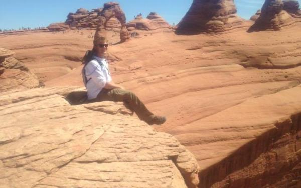 Brent Lary sitting on red sandstone at field camp