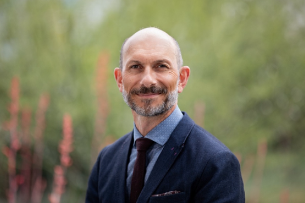 Dr. Louchouarn in a blue suit stands in front of wooded area that is blurred in background