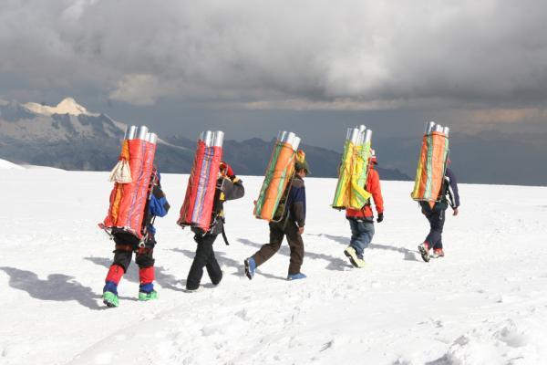 Porters must carry the ice cores down from the drill site after the drilling is finished. (Credit: Lonnie Thompson)