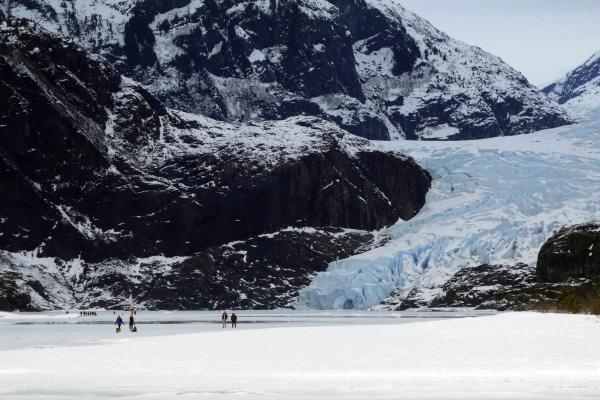 FILE - People walk on a frozen Mendenhall Lake, with Mendenhall Glacier in the background, Feb. 18, 2024, in Juneau, Alaska. A new study says the melting of Alaska’s Juneau icefield, home to more than 1,000 glaciers, is accelerating. Becky Bohrer/AP.
