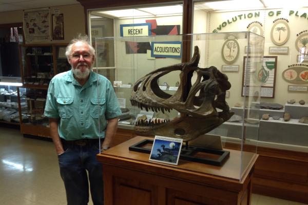 Dale Gnidovec standing next to a replica Cryolophosaurus ellioto skull in the Orton Geological Musem.