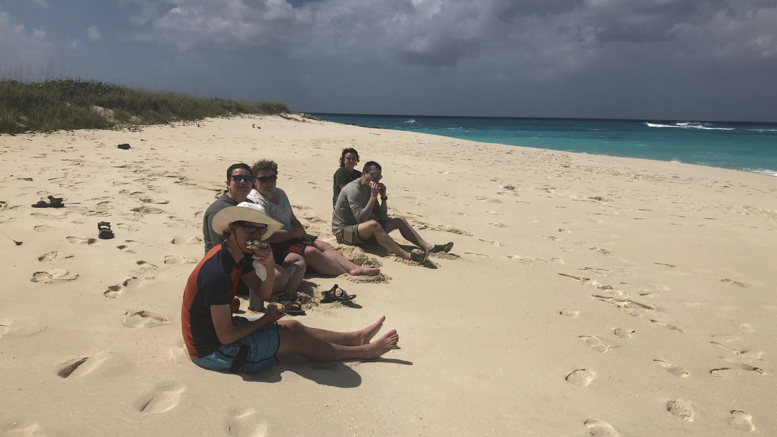 Students sitting on the beach eating lunch