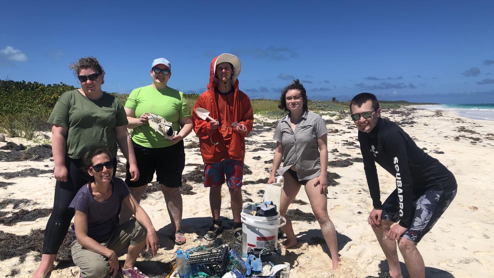 Professor Liz Griffith and five students show their favorite piece of trash they collected during a beach clean up