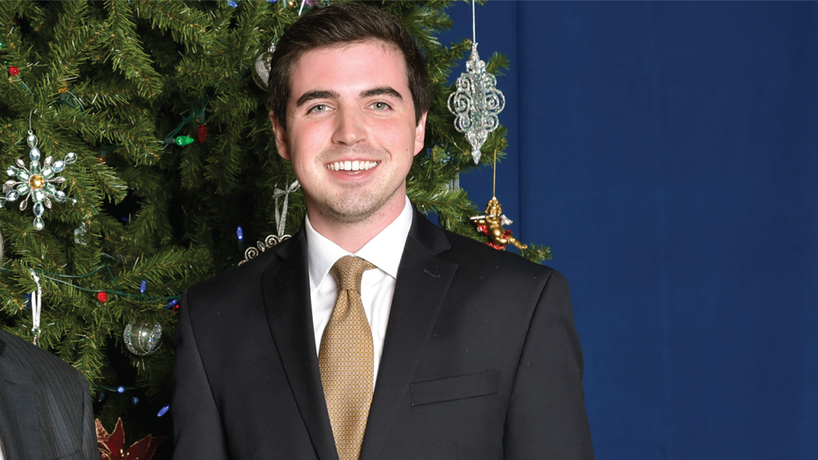 Sean O'Brien smiles in a suit in front of a Christmas tree