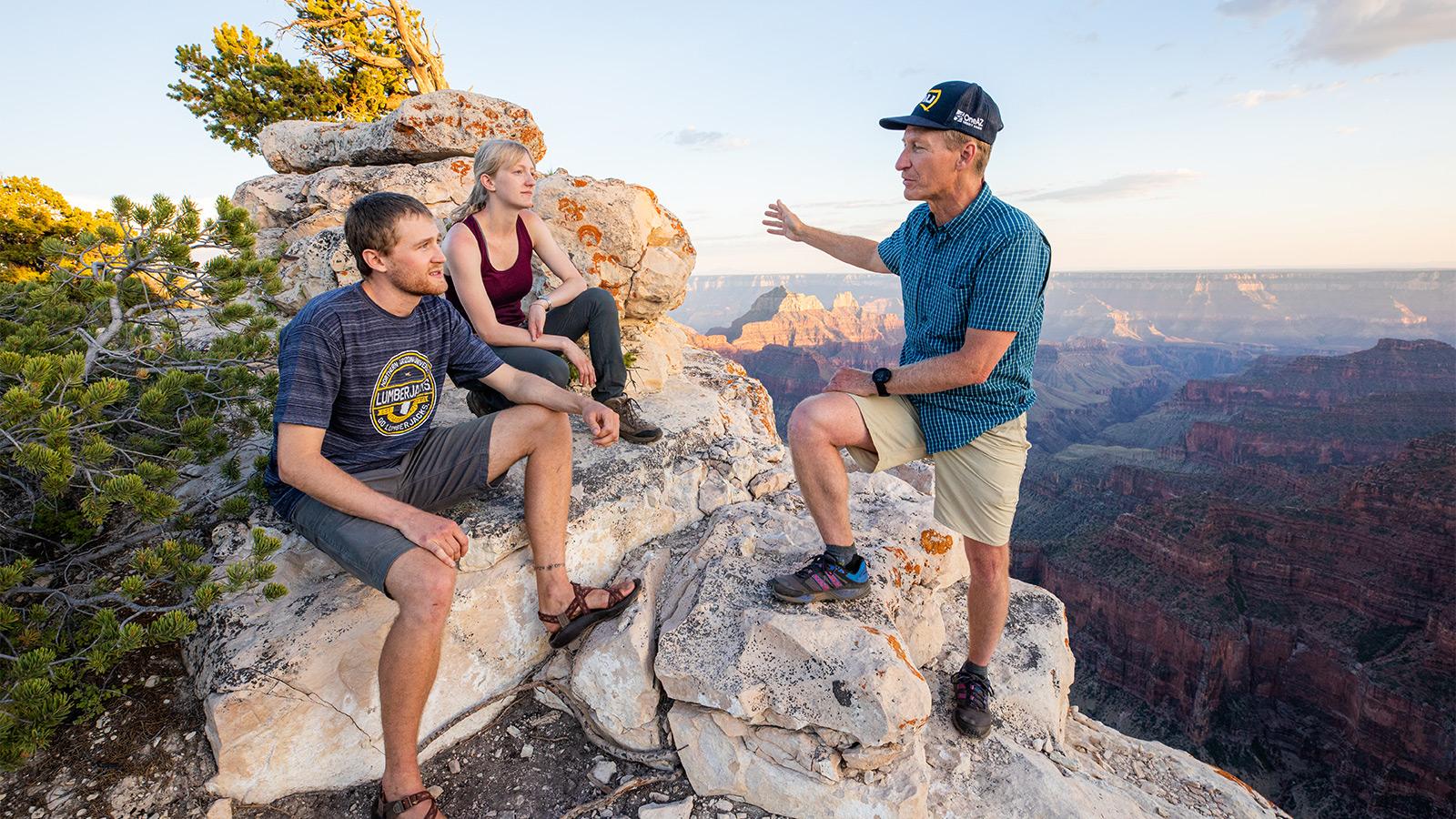 a picture of Abe Springer talking to two young adults on top of a canyon