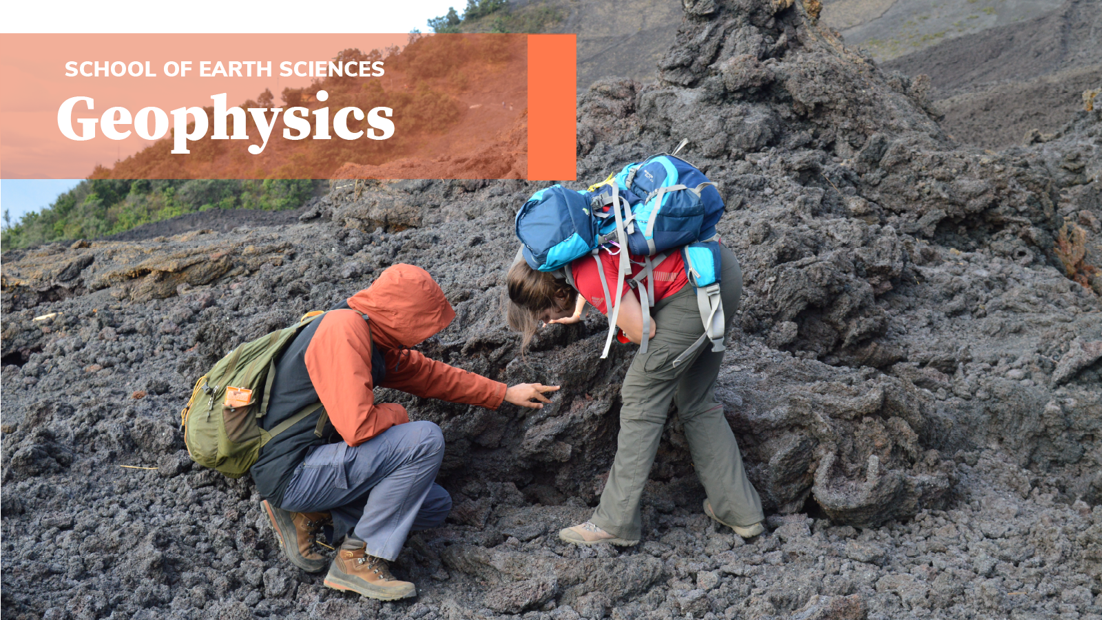 A pair of students inspect hardened lava fields and an orange banner reading "Geophysics" is above them