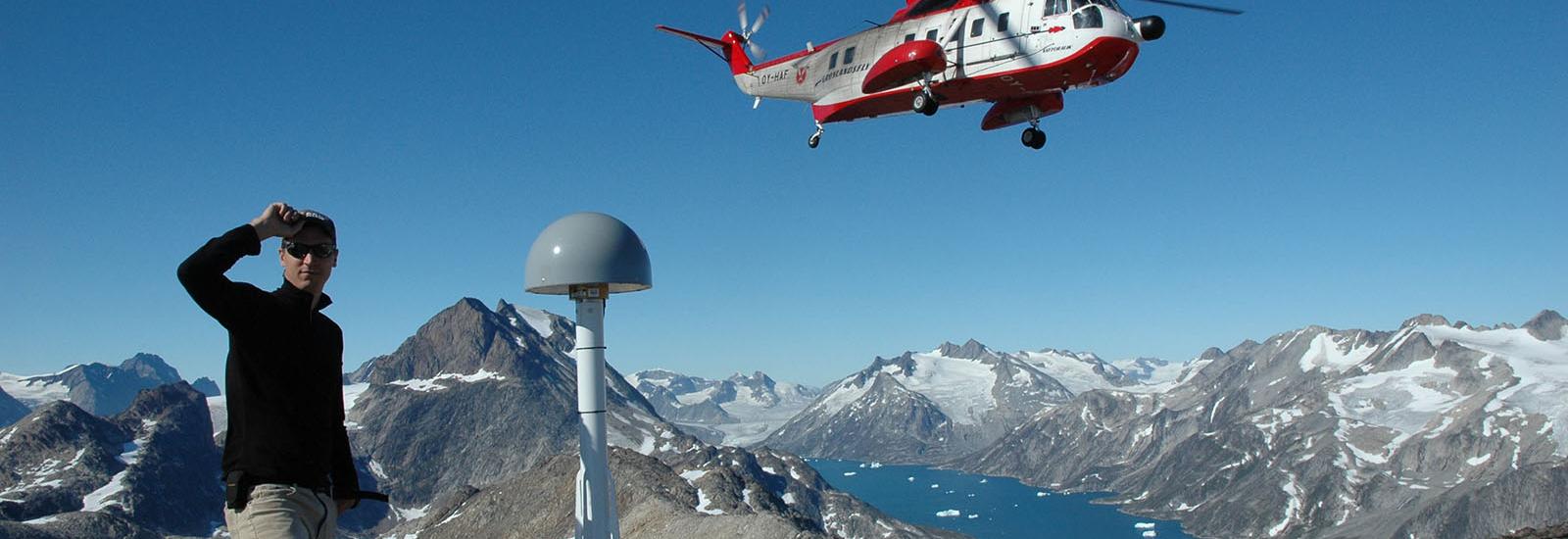 Student next to helicopter on mountain
